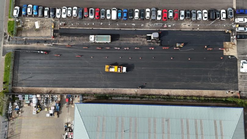 Aerial view of a road with cars and trucks, near a parking area.