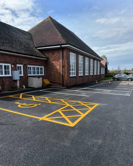 Parking lot with accessible space near a brick building and cloudy sky.