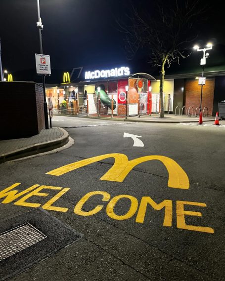 Nighttime view of a McDonald's entrance with a welcoming yellow logo on the ground.