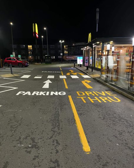 A night view of a parking lot with marked lanes for parking and drive-thru.