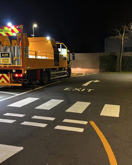 Yellow truck parked near a street exit, with illuminated surroundings at night.
