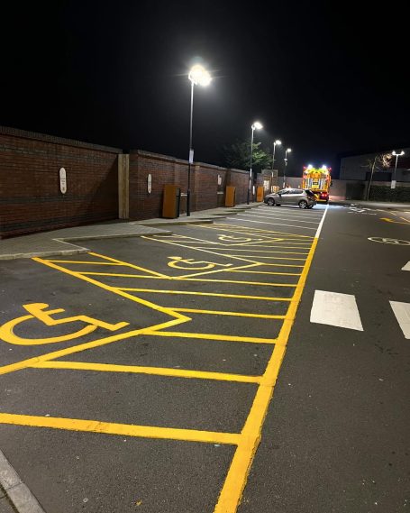 Empty disabled parking bays at night, illuminated by street lighting.